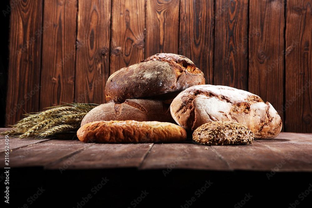 Different kinds of bread and bread rolls on board from above. Kitchen or bakery Different kinds of bread and bread rolls on board from above. Kitchen or bakery