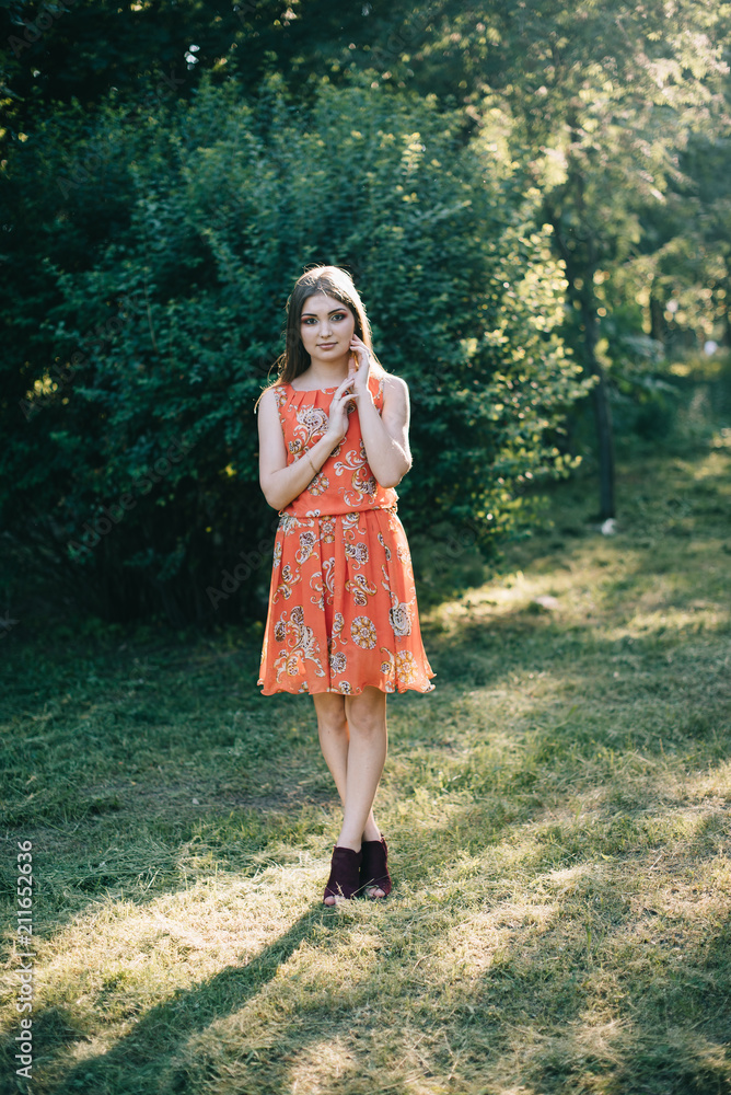Beautiful young girl in a summer red dress in a park Beautiful young girl in a summer red dress in a park
