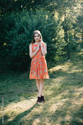 Beautiful young girl in a summer red dress in a park © prokop.photo