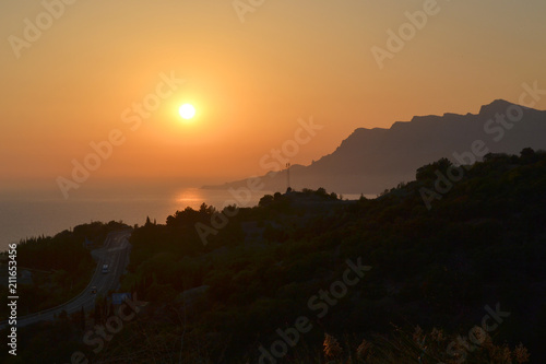 Sunset  setting sun over the sea and mountains