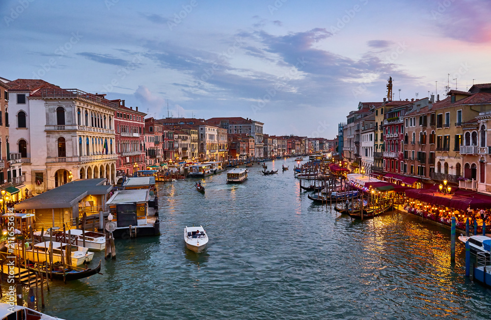 Fototapeta premium Canal Grande with boats and lights in Venice at Sunset. Next to famous Rialto Bridge and the Street 