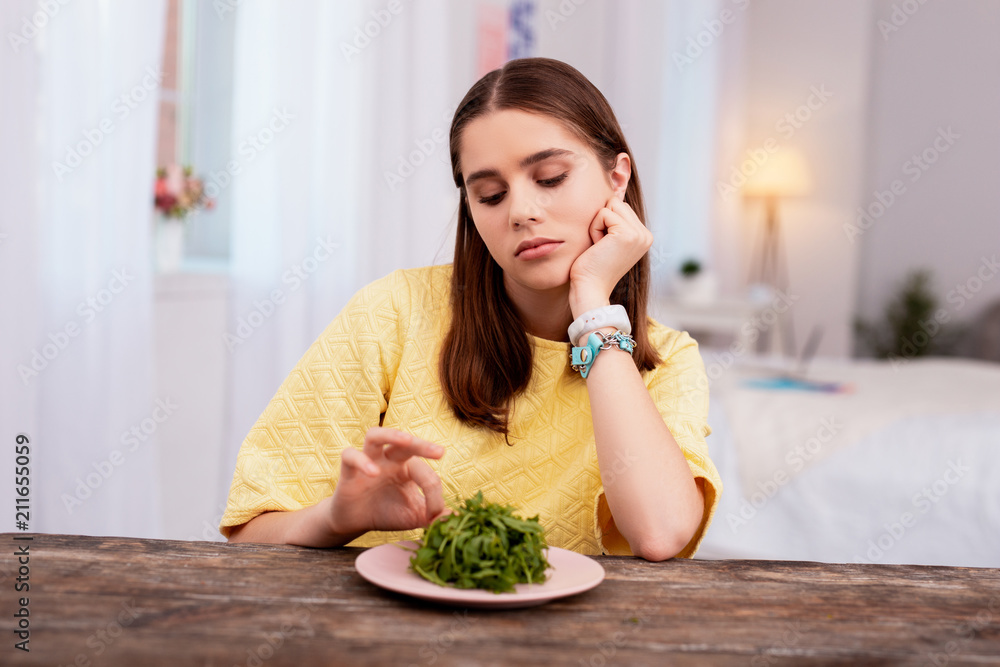 Weight loss. Bored teen girl looking at salad and leaning on hand Weight loss. Bored teen girl looking at salad and leaning on hand