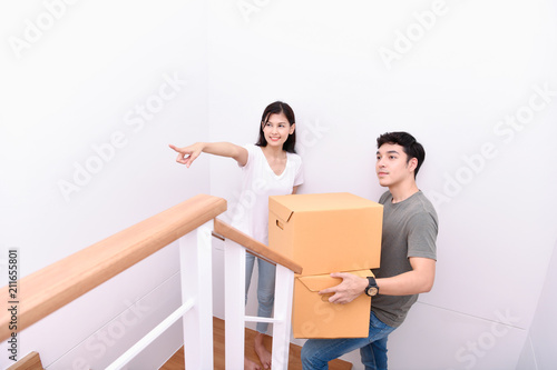 Moving house Concept. Asian young man is carrying his belongings. Young Asian women are holding their stuff in a paper box. Young are happy in the new house.