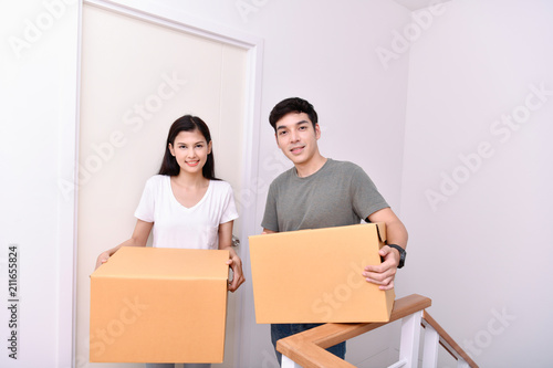 Moving house Concept. Asian young man is carrying his belongings. Young Asian women are holding their stuff in a paper box. Young are happy in the new house.