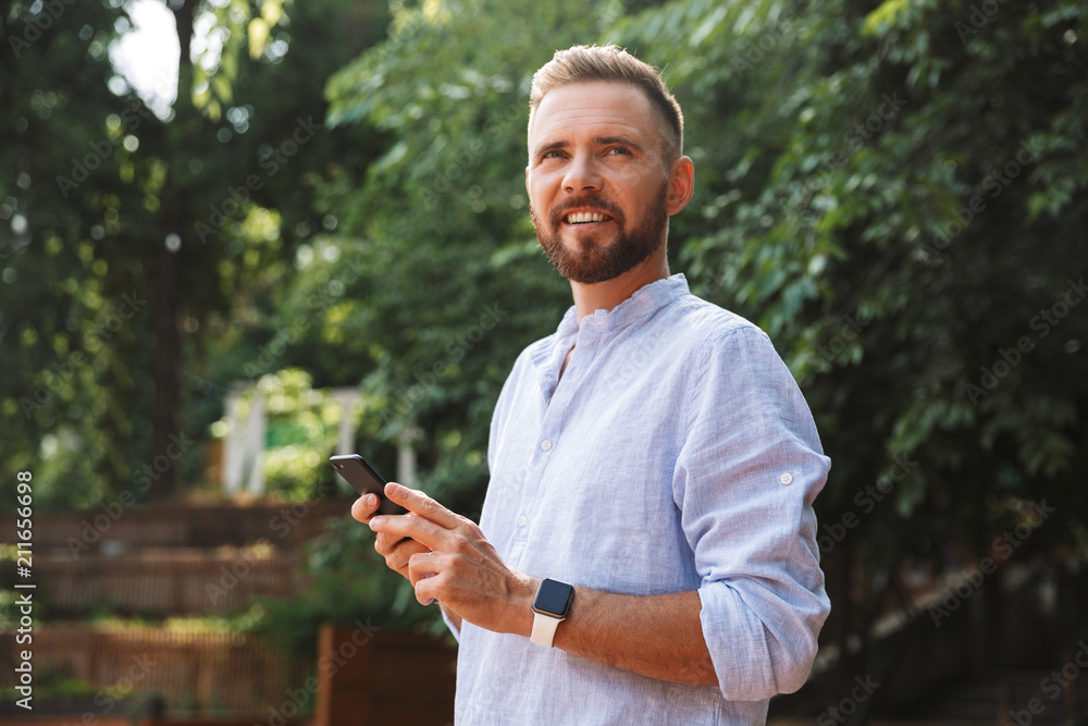 Happy young bearded man outdoors using mobile phone. Happy young bearded man outdoors using mobile phone.