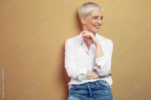 blonde junge Frau steht an der Wand photo