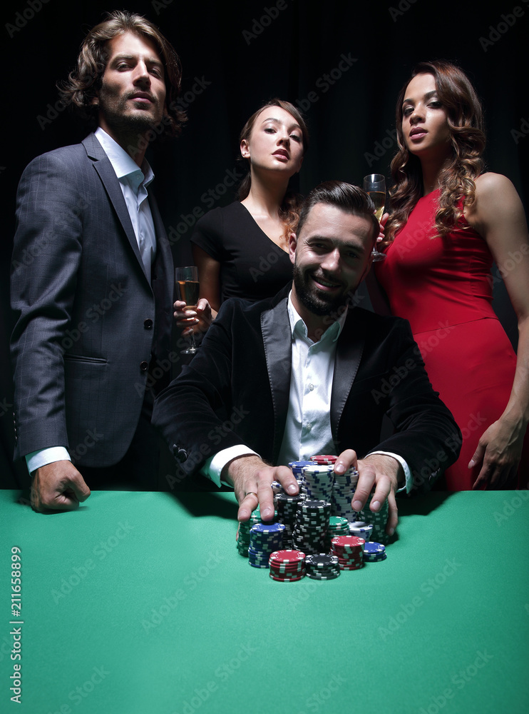 People standing at the table, looking, while a person is betting People standing at the table, looking, while a person is betting