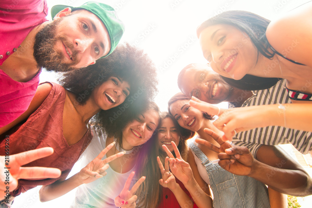 Obraz premium group of friends in a circle having fun. cheerful university students taking photo together smiling and gesturing peace sign.