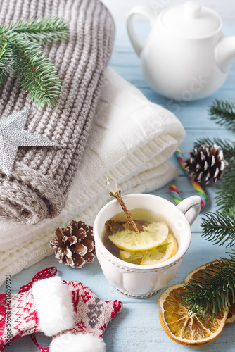 A cup of tea for the new year. A cozy plaid, a knitted scarf and hot tea on blue wooden background