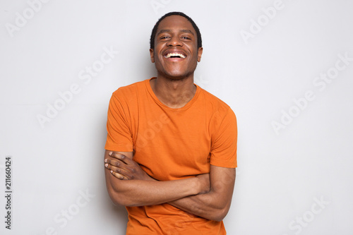 happy black guy laughing with arms crossed against white background