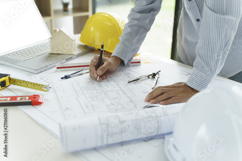 Architect or engineer hands working on blueprint plans  with a pencil and laptop a ruler, calculator,  and engineering tools.    Woman architect or engineer working on blueprint in office.   photo