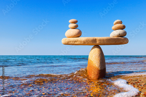 Canvas Print Symbolic scales of the stones, illuminated by the evening sun, against the sea, close-up