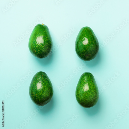 Green avocado pattern on blue background. Top view. Pop art design, creative summer food concept. Organic avocadoes in minimal flat lay style. Square crop