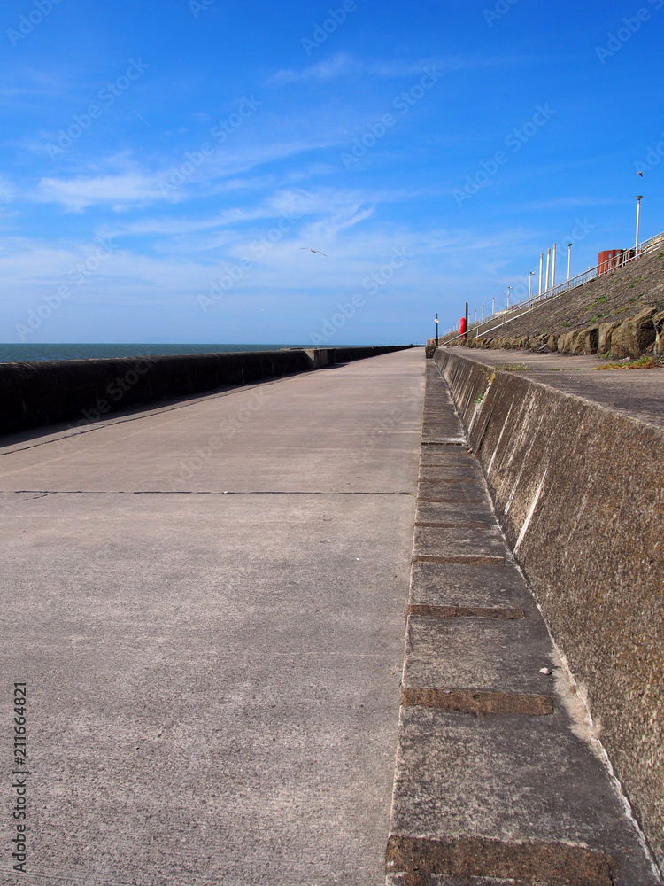 the long concrete pedestrian walkway along the seawall in blackpool lancashire with summer sunshine and sea