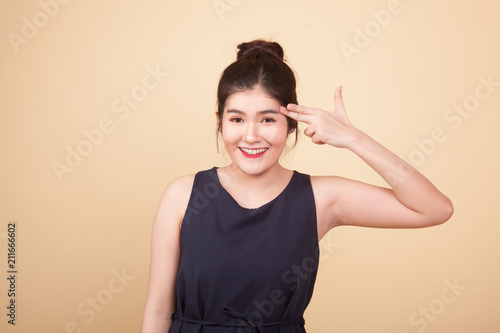 Beautiful young Asian woman holding fingers in gun gesture.