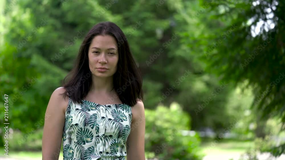 A portrait of a cute asian woman looking into camera in the park.