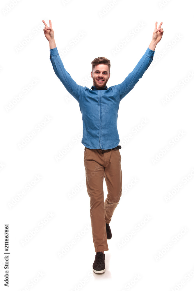 smiling casual man stepping and making victory sign smiling casual man stepping and making victory sign
