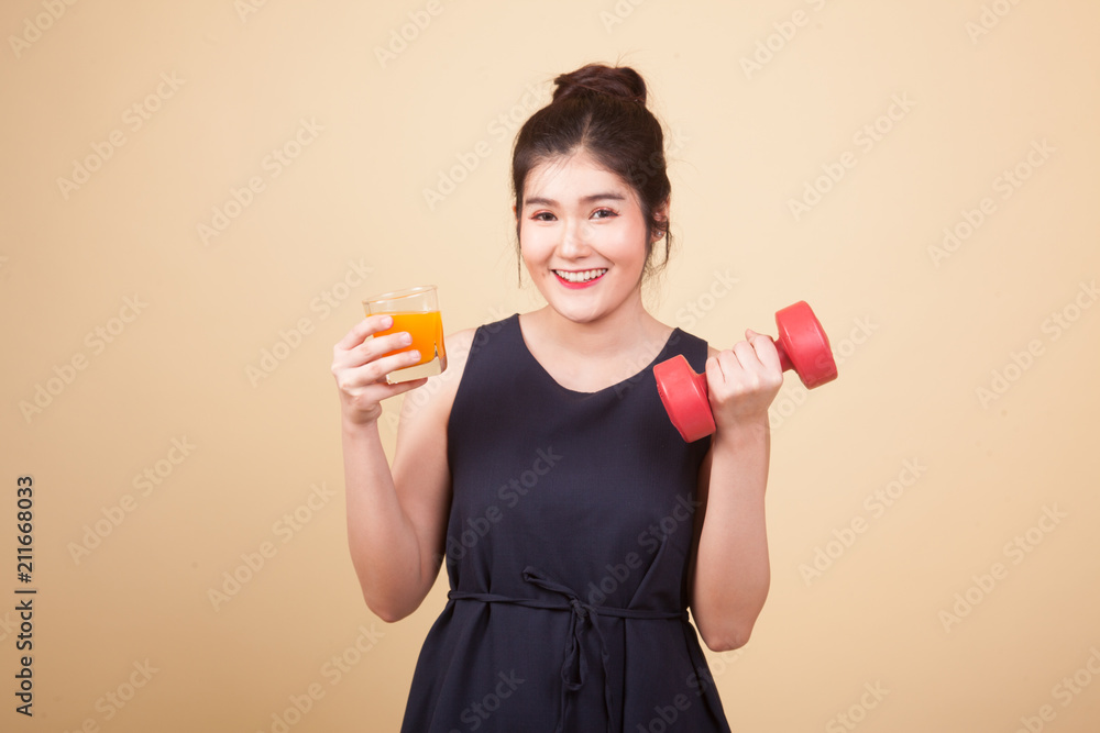 Young Asian woman with dumbbell drink orange juice. Young Asian woman with dumbbell drink orange juice.