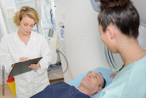 Doctor filling in form, patient layed on bed