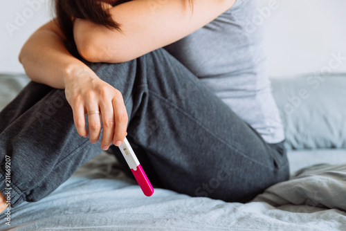 sad woman on bed with negative pregnancy test