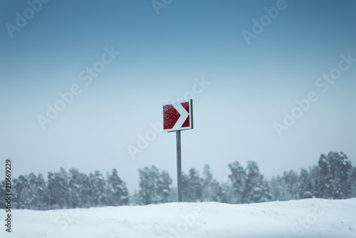 Red arrow signs in a snow. A forest on the background