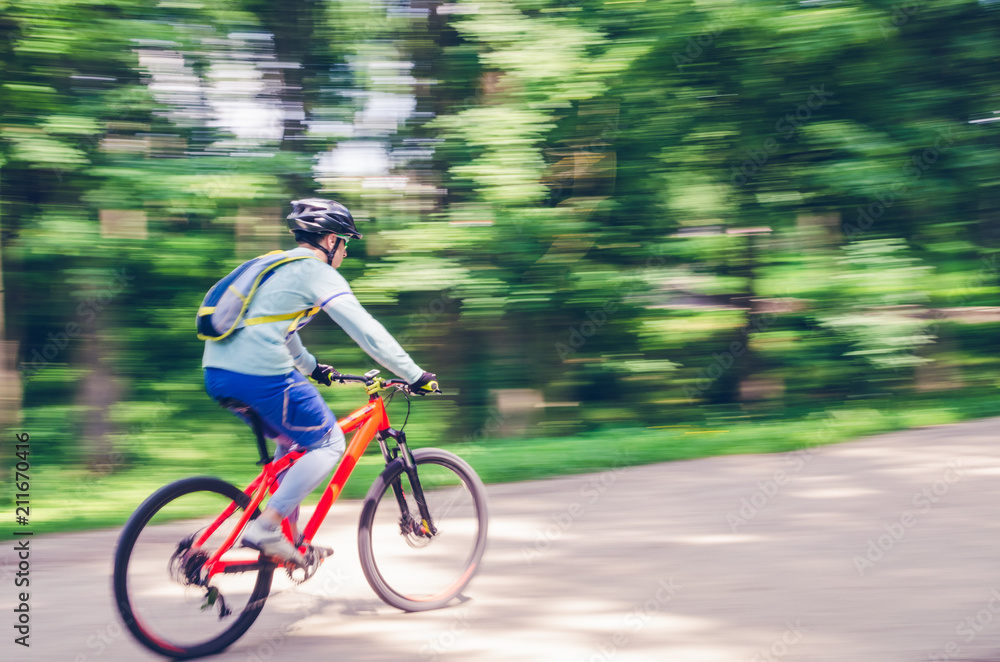 A cyclist in a helmet rides a bicycle path, motion blur