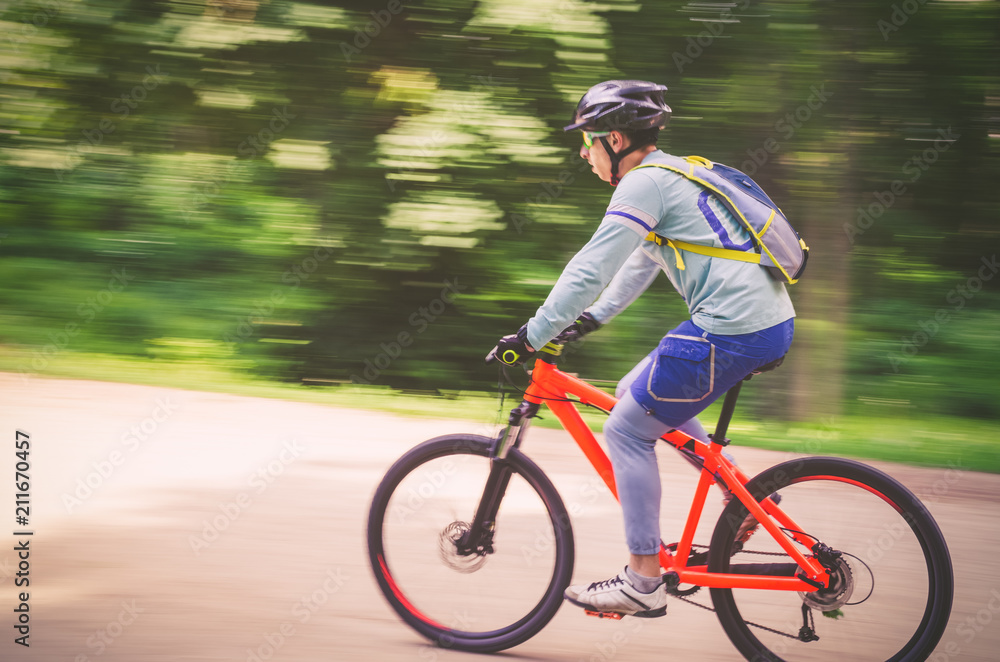 A cyclist in a helmet rides a bicycle path, motion blur A cyclist in a helmet rides a bicycle path, motion blur