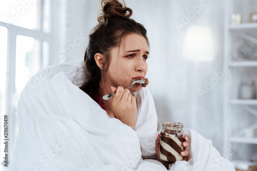 Watching melodrama. Woman feeling emotional while watching melodrama and eating chocolate spread with spoon