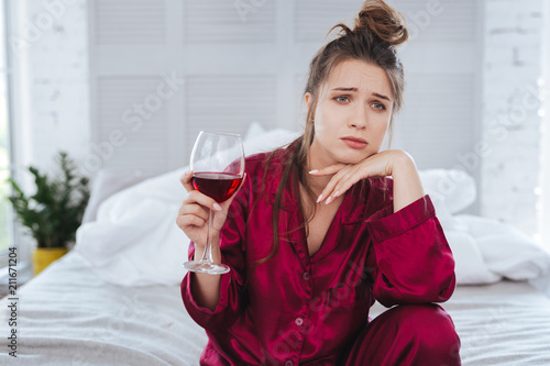 Lonely woman. Lonely emotional woman feeling impassioned wearing pajama drinking alcohol alone