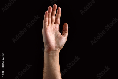 Male palm raised up, isolated on a dark background. Isolate