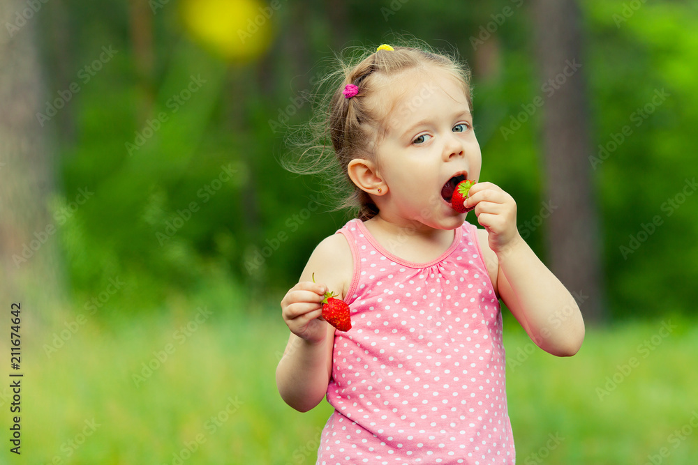 Little girl eating strawberry in nature. Child enjoys a delicious berry. Little girl eating strawberry in nature. Child enjoys a delicious berry.