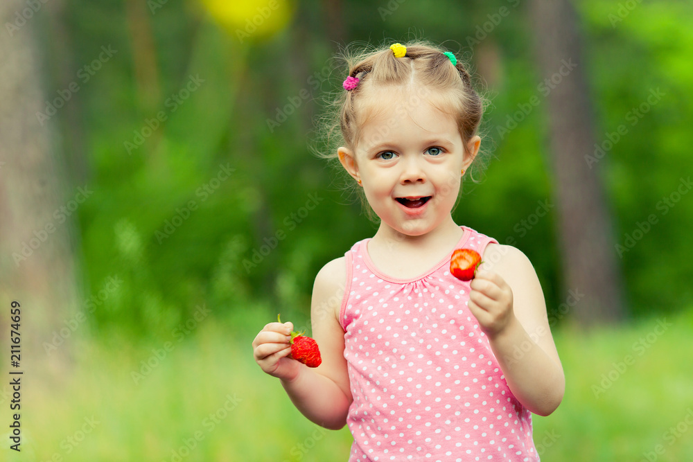 Little girl eating strawberry in nature. Child enjoys a delicious berry. Little girl eating strawberry in nature. Child enjoys a delicious berry.