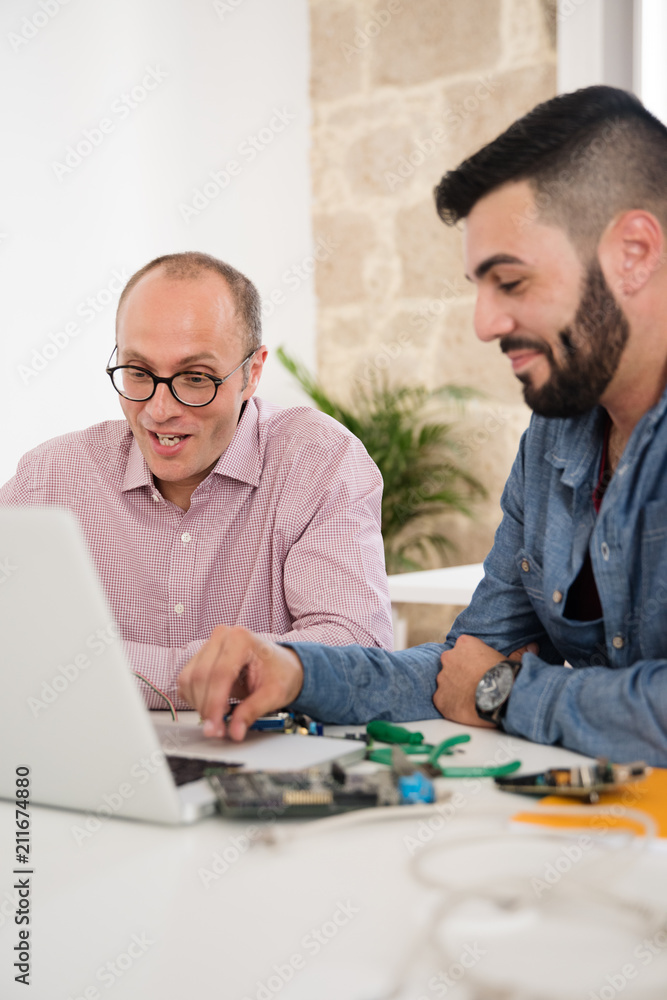 Two men looking at a laptop and laughing Two men looking at a laptop and laughing