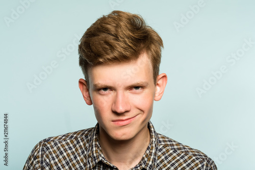 smug smile. man with a self satisfied smirk. portrait of a young guy on light background. emotion facial expression. feelings and people reaction. photo