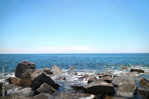 Picture of a sea and small rocks/stones in front, sunny summer day and blue sky in Portimao, Portugal.