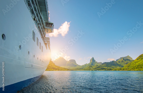 Side view of anchored cruise ship at sunset. Mountain background.