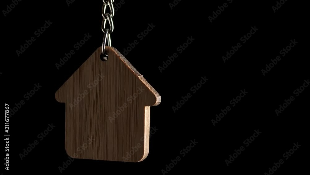 Wooden key holder with house shape hanging and rotating on black background Wooden key holder with house shape hanging and rotating on black background