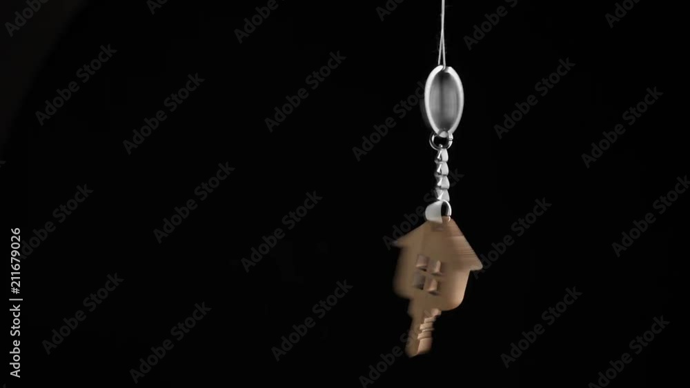 Wooden key holder with house shape hanging and rotating on black background Wooden key holder with house shape hanging and rotating on black background