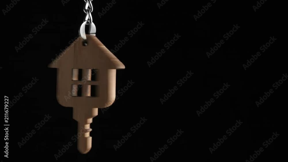 Wooden key holder with house shape hanging and rotating on black background Wooden key holder with house shape hanging and rotating on black background