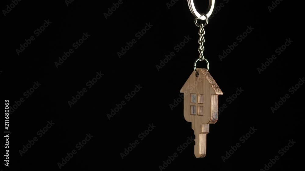 Wooden key holder with house shape hanging and rotating on black background Wooden key holder with house shape hanging and rotating on black background