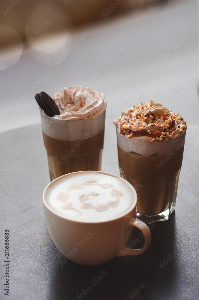 Milkshake macchiato overshake cappuccino on a wooden table in a coffee house. Cups of coffee on wooden background Trendy food concept. Milkshake macchiato overshake cappuccino on a wooden table in a coffee house. Cups of coffee on wooden background Trendy food concept.