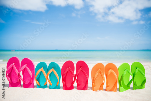 colorful flip flop on sandy beach, green sea and blue sky background for summer holiday and vacation concept.