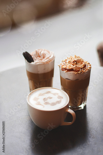 Milkshake macchiato overshake cappuccino on a wooden table in a coffee house. Cups of coffee on wooden background Trendy food concept.