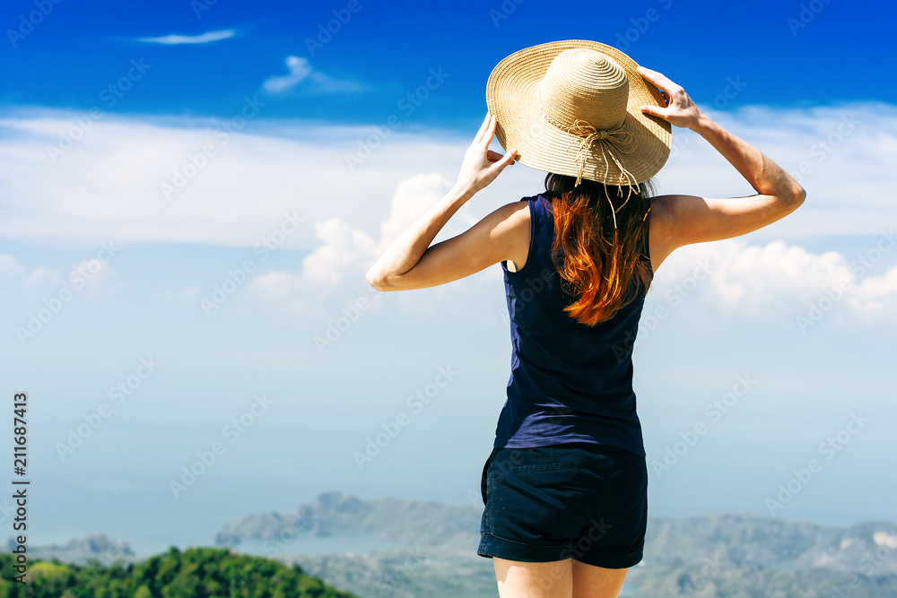 Young traveling woman wearing hat and standing on the top of the mountain cliff, Langkawi island