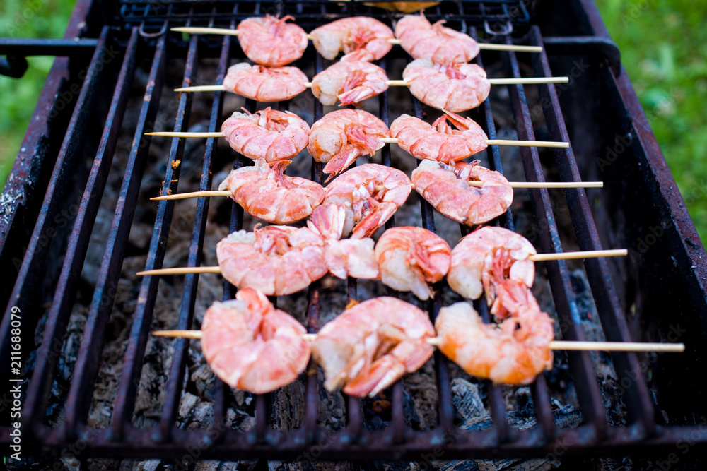 Skewers of shrimp langoustine on the grill, cooking outdoors in summer