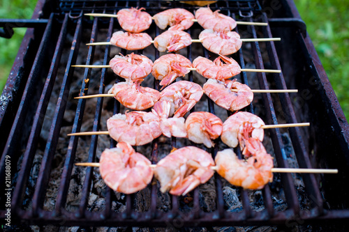 Skewers of shrimp langoustine on the grill, cooking outdoors in summer