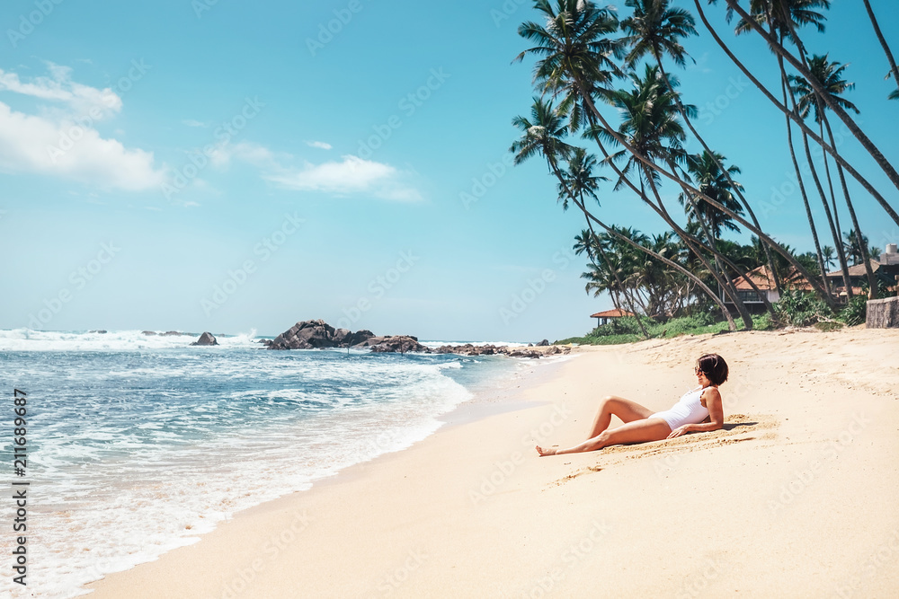 Obraz premium Woman takes sunbath on tropical beach. Island paradise