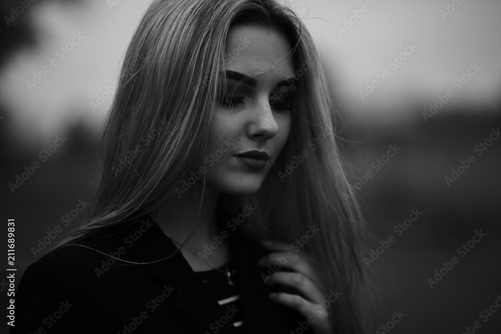 Portrait photos of a girl in a black coat.Girl posing in cloudy weather.Black and white photos of a beautiful blonde Portrait photos of a girl in a black coat.Girl posing in cloudy weather.Black and white photos of a beautiful blonde