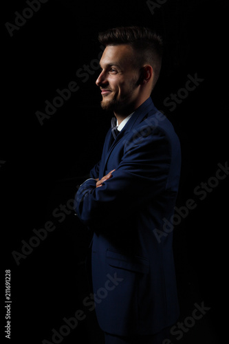 young man on a black background in a suit / hands crossed
