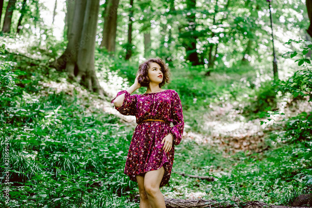 Sweet girl with curly hair poses in the park